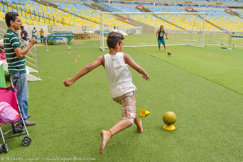 Imagem de um menino jogando bola no Maracanã.